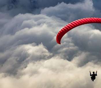 Photo of a person paragliding with a dramatic cloudy background
