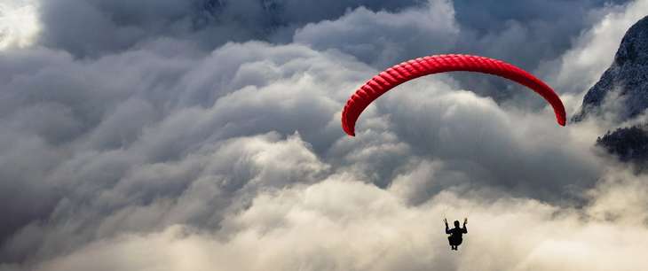 Photo of a person paragliding with a dramatic cloudy background