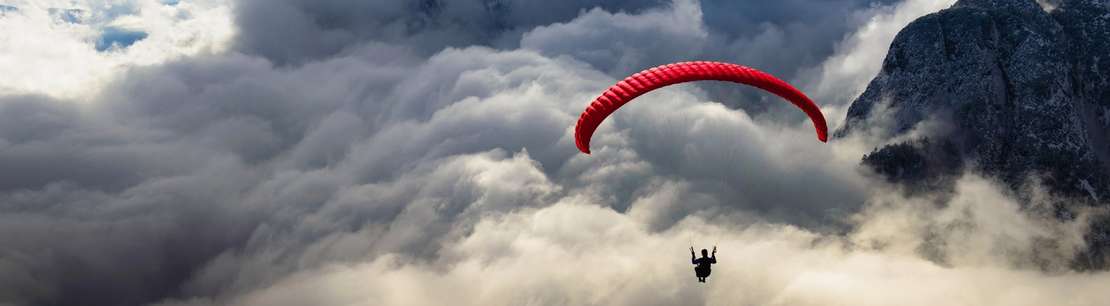 Photo of a person paragliding with a dramatic cloudy background