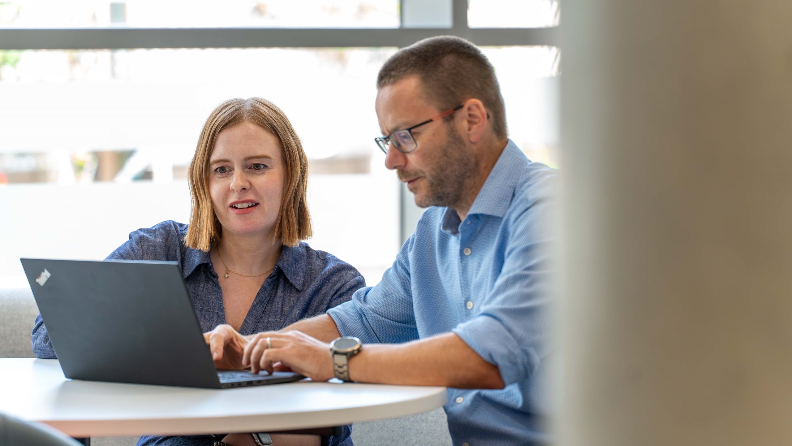 a man and a woman working together on a laptop computer