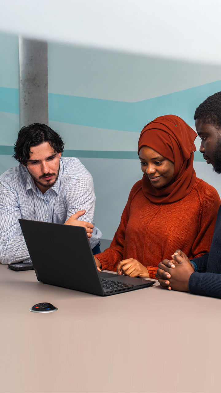 A group of happy colleagues working together around a laptop.