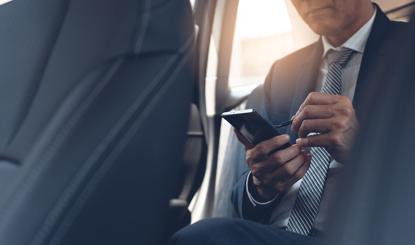 An executive using his mobile device in a car