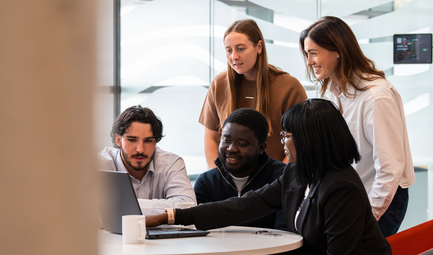 A group of audit colleagues reviewing a project on a laptop computer