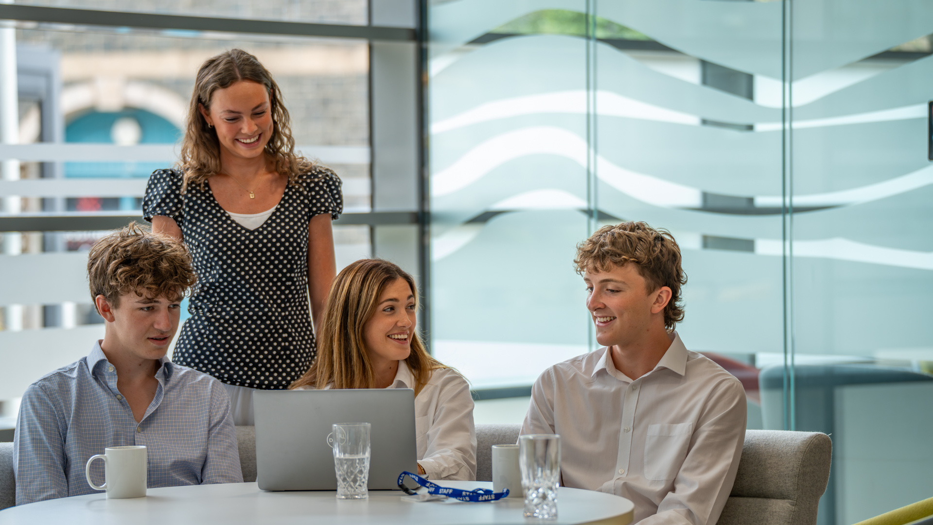 3 early in career team memberslearning from a more experienced manager , sat round a laptop