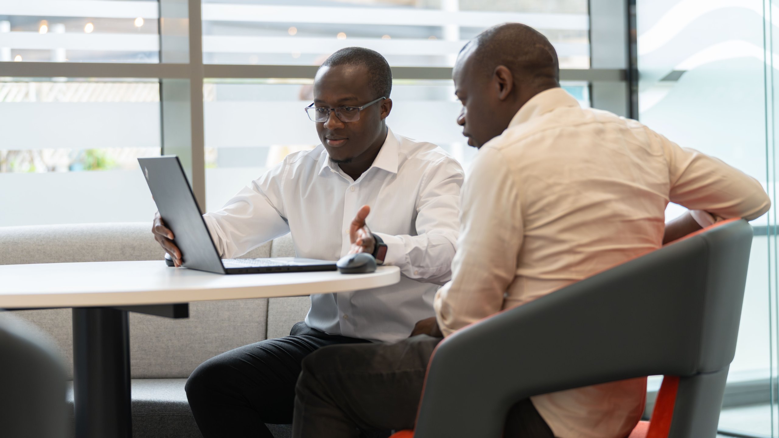 Two men discussing a business problem while looking at a laptop computer
