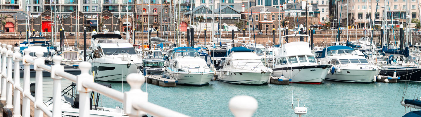 Sunny marina and yachts floating at mid-tide.