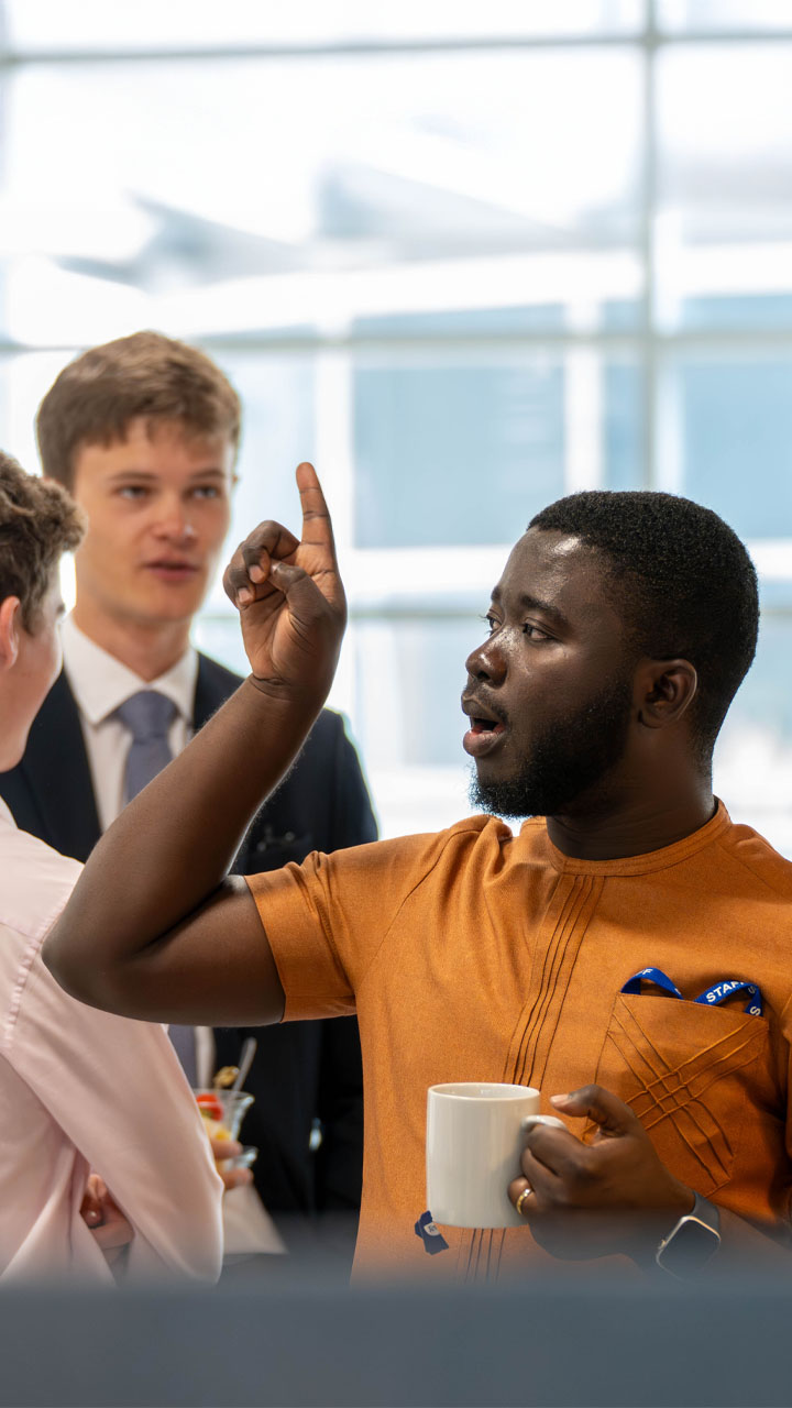 Young trainee associate wearing a traditional Kaftan pointing upwards.
